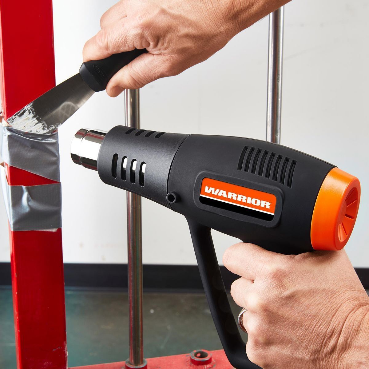 WARRIOR 1500 Watt Dual Temperature Heat Gun in use, efficiently stripping paint from a surface.