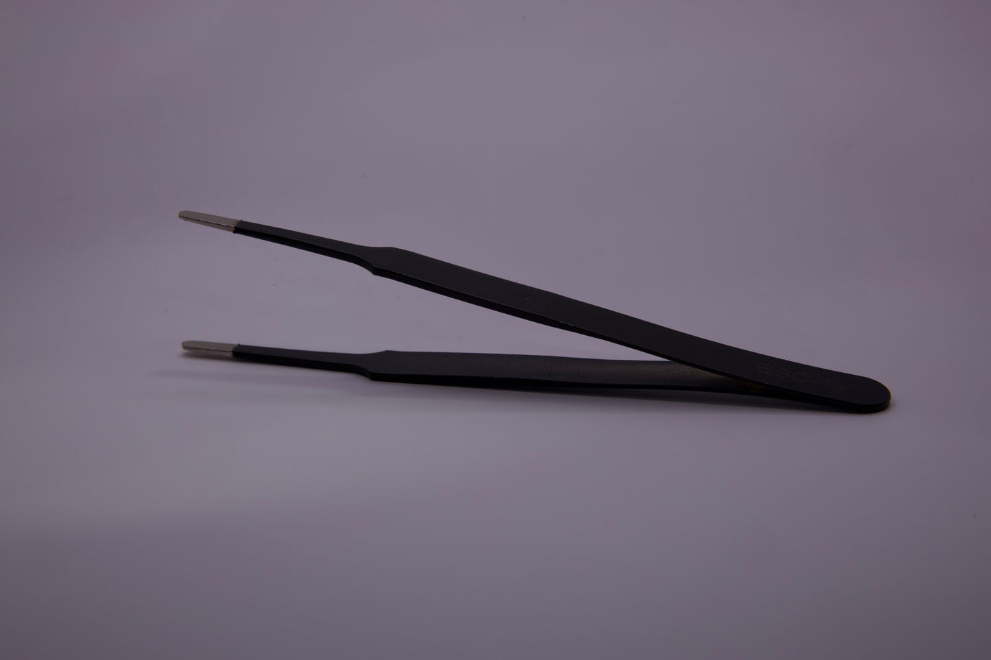 Professional Precision Tweezers extracting a dust particle from wrap film.